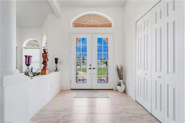 Entrance foyer with french doors, high vaulted ceiling, beam ceiling, and baseboards