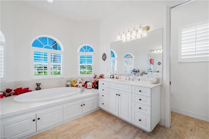 Bathroom featuring vanity, a garden tub, and a towering ceiling