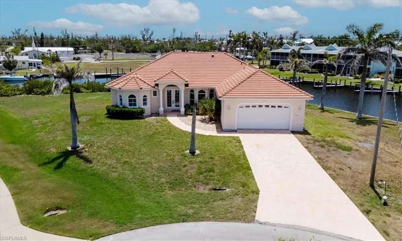 Mediterranean / spanish-style house with french doors, a tiled roof, a garage, and a front yard