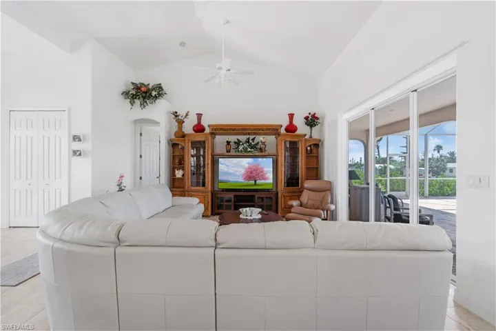 Living area featuring ceiling fan, high vaulted ceiling, and arched walkways