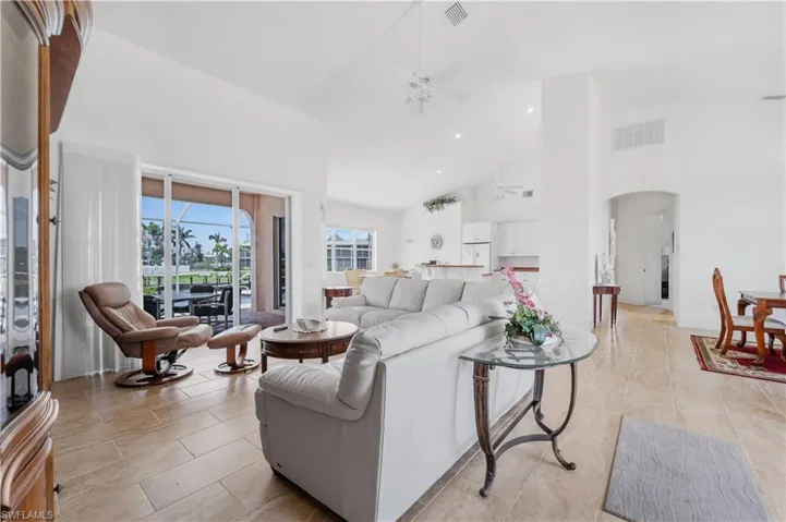 Living area with ceiling fan, arched walkways, high vaulted ceiling, light tile patterned floors, and recessed lighting