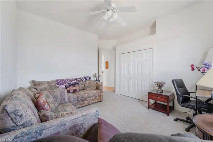 Carpeted home office featuring ceiling fan