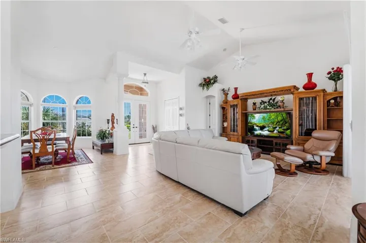 Living room featuring high vaulted ceiling, a ceiling fan, and french doors