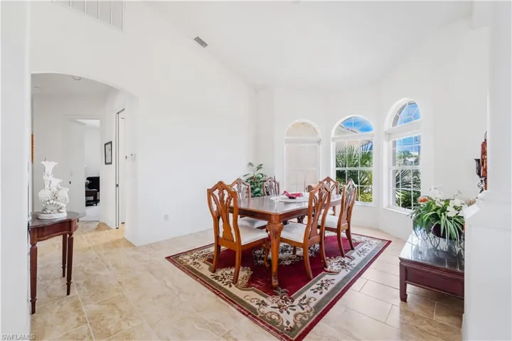 Dining space with arched walkways, a towering ceiling, and light tile patterned floors