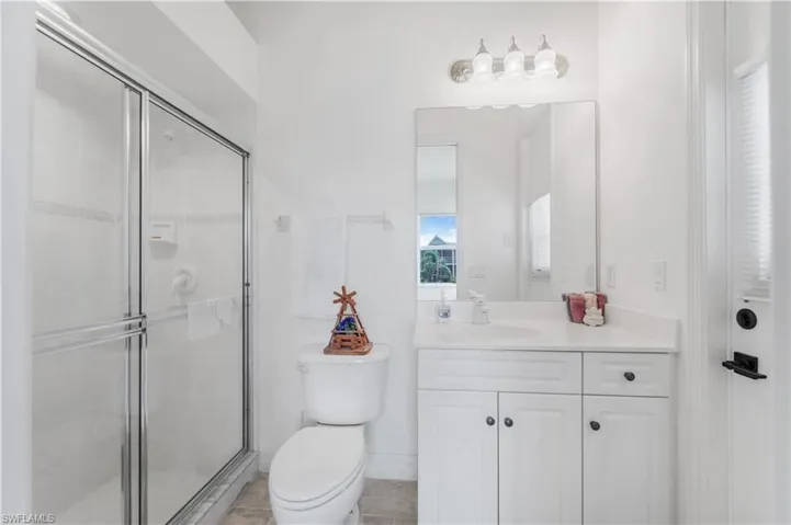 Full bathroom with toilet, vanity, and a stall shower