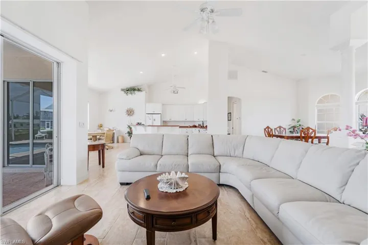 Living room featuring ceiling fan, vaulted ceiling, and decorative columns