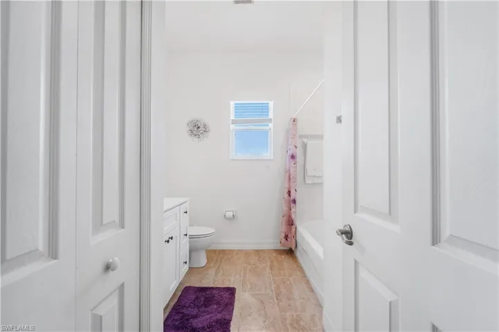 Bathroom featuring toilet, shower / bath combo, vanity, and baseboards