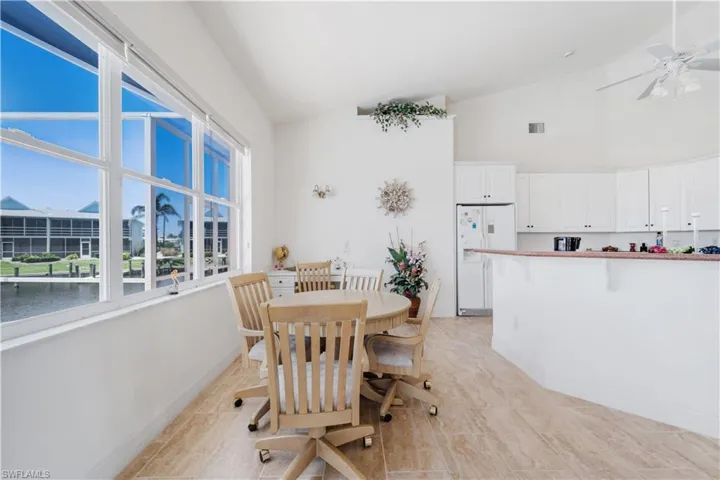 Dining room with high vaulted ceiling, ceiling fan, plenty of natural light, light tile patterned floors, and baseboards