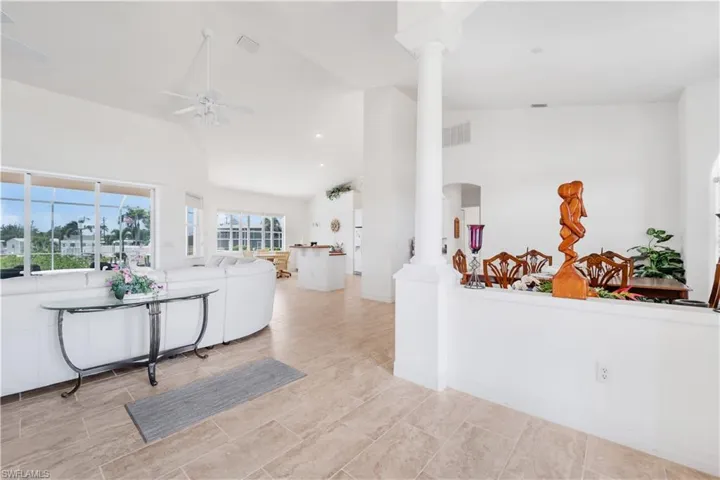 Living area with decorative columns, plenty of natural light, ceiling fan, high vaulted ceiling, and recessed lighting