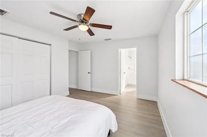 Bedroom with wood finished floors, ceiling fan, ensuite bath, and a closet