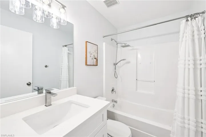 Bathroom featuring vanity and shower / bathtub combination with curtain