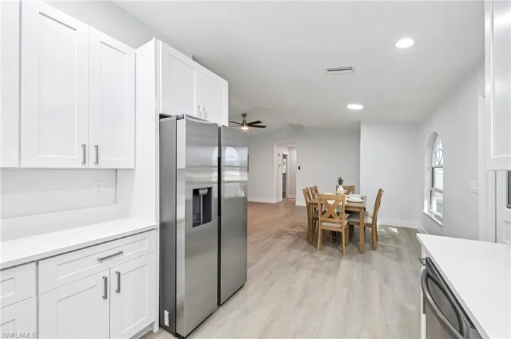 Kitchen featuring stainless steel appliances, white cabinets, ceiling fan, light wood finished floors, and recessed lighting