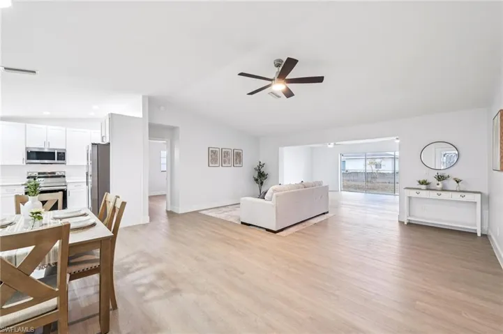 Living room with a ceiling fan, light wood-style flooring, vaulted ceiling, and recessed lighting