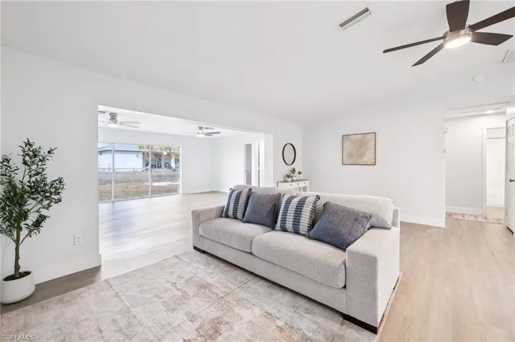 Living room featuring ceiling fan, light wood-style floors, and lofted ceiling