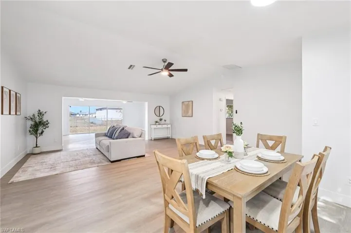 Dining room with ceiling fan, light wood-style flooring, and lofted ceiling