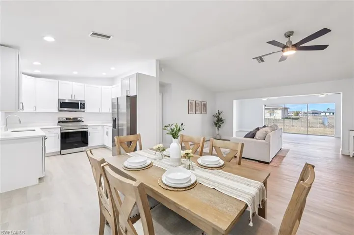 Dining space featuring lofted ceiling, light wood-style floors, and ceiling fan