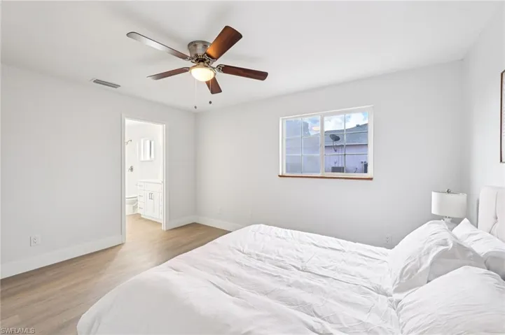 Bedroom with light wood-style floors, a ceiling fan, and ensuite bathroom