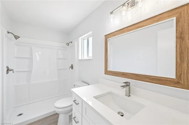 Full bathroom featuring vanity, a shower stall, and light wood-style flooring