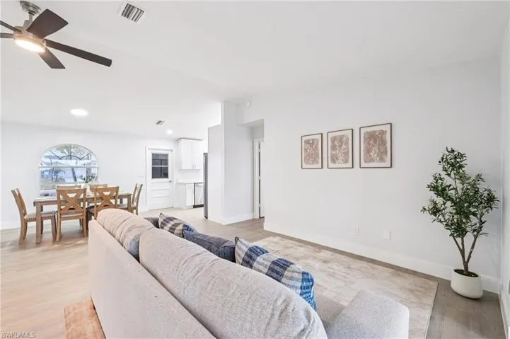 Living room featuring a ceiling fan, light wood-style flooring, and vaulted ceiling