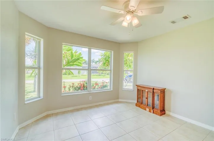 Spare room featuring ceiling fan, light tile patterned floors, and a wealth of natural light