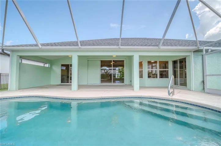 View of swimming pool featuring glass enclosure and a patio area