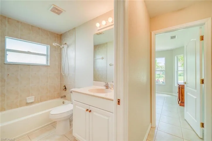 Full bathroom with tiled shower / bath, vanity, toilet, and tile patterned flooring
