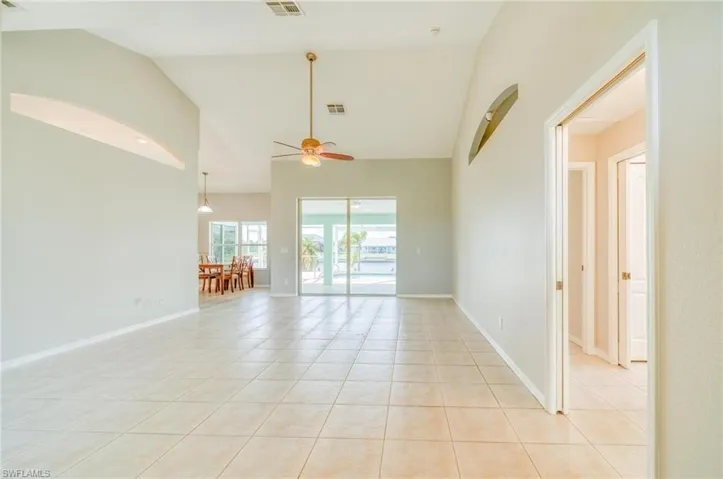 Tiled spare room featuring ceiling fan and high vaulted ceiling
