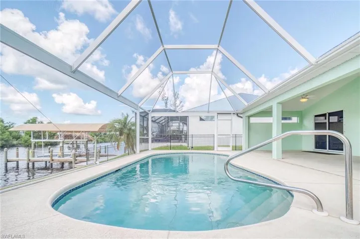 View of swimming pool with glass enclosure and a patio area
