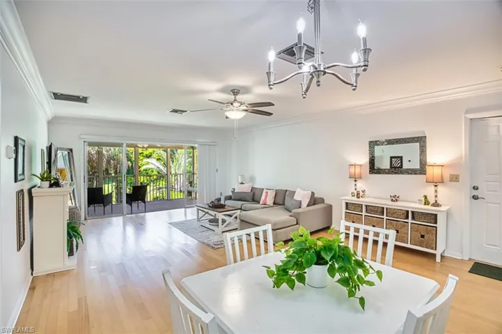 Dining room featuring crown molding, light wood finished floors, a chandelier, and a ceiling fan