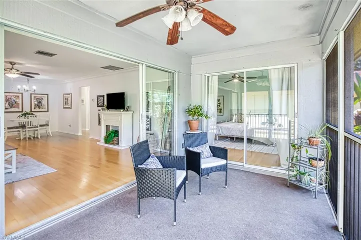 Sunroom with a ceiling fan and a fireplace with raised hearth