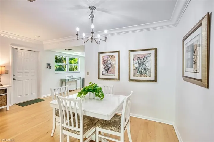Dining space with ornamental molding, light wood-style floors, and a chandelier