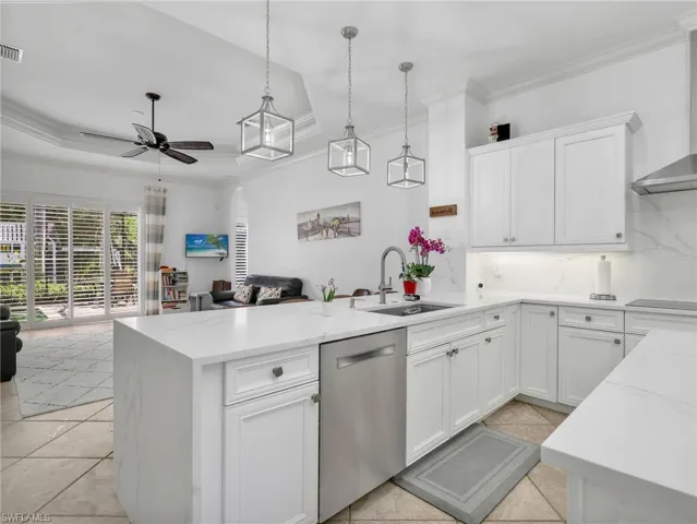 Kitchen with open floor plan, white cabinetry, backsplash, stainless steel dishwasher, and crown molding