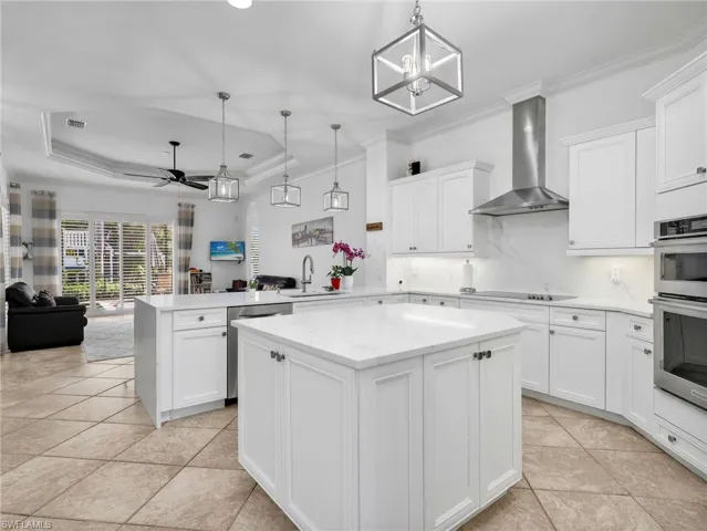 Kitchen featuring a peninsula, crown molding, open floor plan, white cabinetry, and a center island