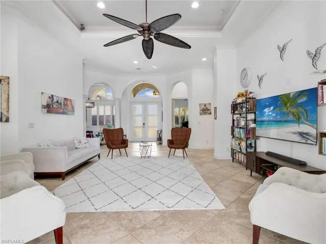 Living area with arched walkways, a ceiling fan, recessed lighting, french doors, and a tray ceiling
