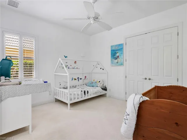 Carpeted bedroom with ceiling fan and a closet