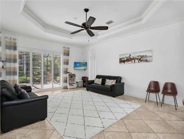 Living room featuring a ceiling fan, arched walkways, and ornamental molding