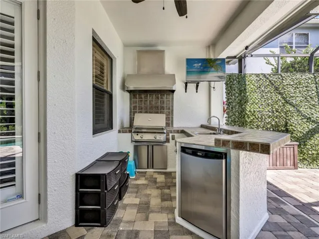 View of patio featuring an outdoor kitchen, glass enclosure, and ceiling fan