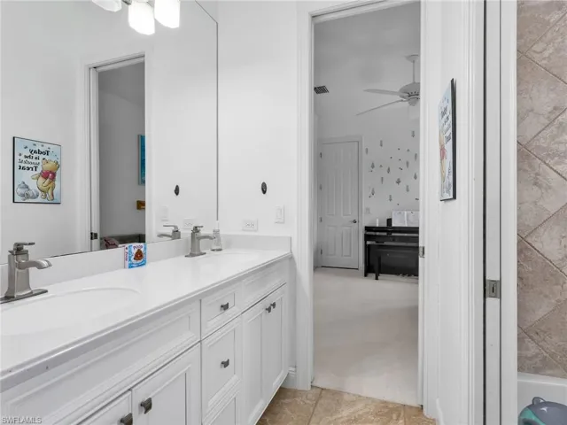 Full bathroom with double vanity, light colored carpet, and ceiling fan