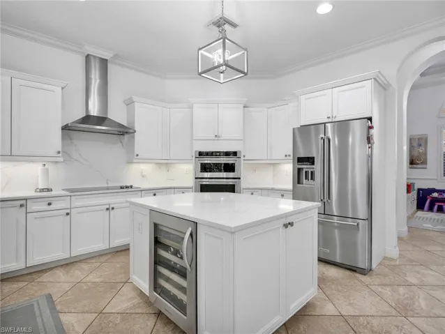 Kitchen with stainless steel appliances, decorative backsplash, arched walkways, wine cooler, and crown molding