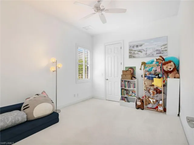 Bedroom with light colored carpet and a ceiling fan