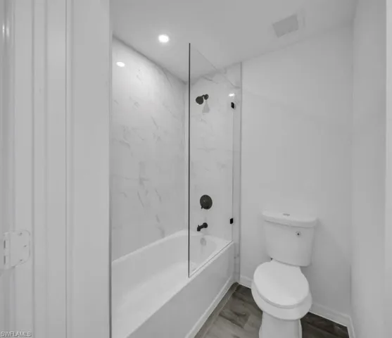 Full bath featuring  shower combination, wood finished floors, and recessed lighting