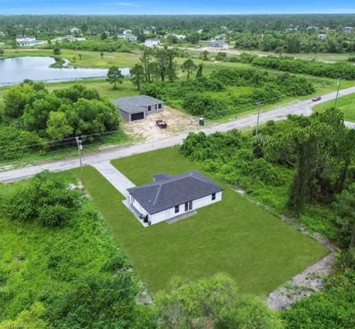 View of subject property with a tree filled landscape and a nearby body of water