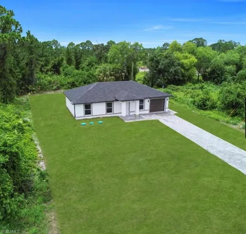 Ranch-style house featuring a front lawn, driveway, roof with shingles, and a garage