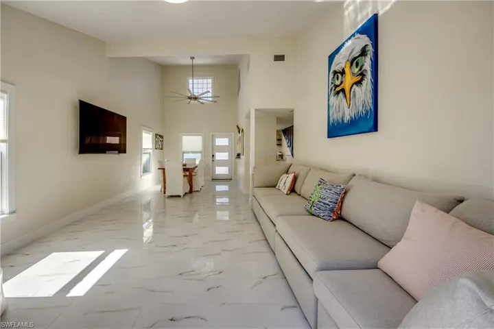 Living room featuring a high ceiling, light marble finish flooring, and a ceiling fan