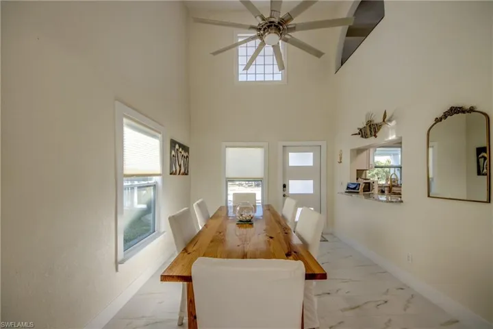Dining area featuring light marble finish flooring, a towering ceiling, and ceiling fan