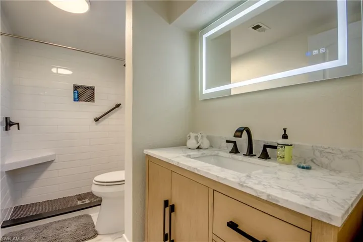 Bathroom with vanity, a textured wall, and a tile shower