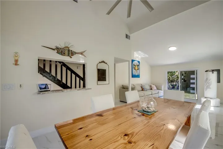 Dining room with vaulted ceiling, stairway, a ceiling fan, and marble finish floors