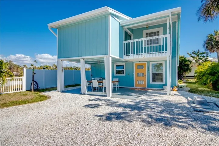 Rear view of property featuring a patio area, ceiling fan, a carport, outdoor dining space, and a balcony