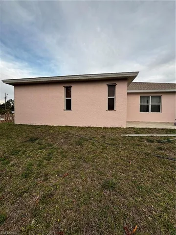 View of property exterior with a lawn and stucco siding