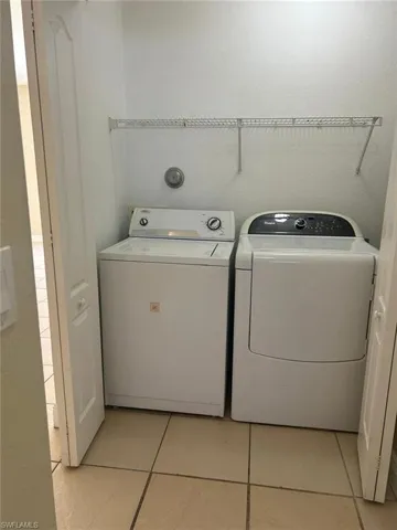 Laundry area featuring light tile patterned floors and washer and dryer